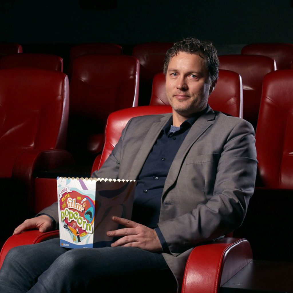 Arild Kalkvik sitter i en kinosal med et popcornbeger på fanget