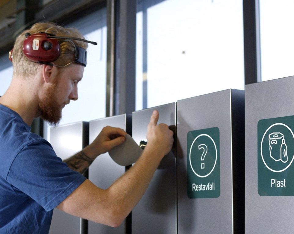 En mann monterer en etikett på en avfallsbeholder