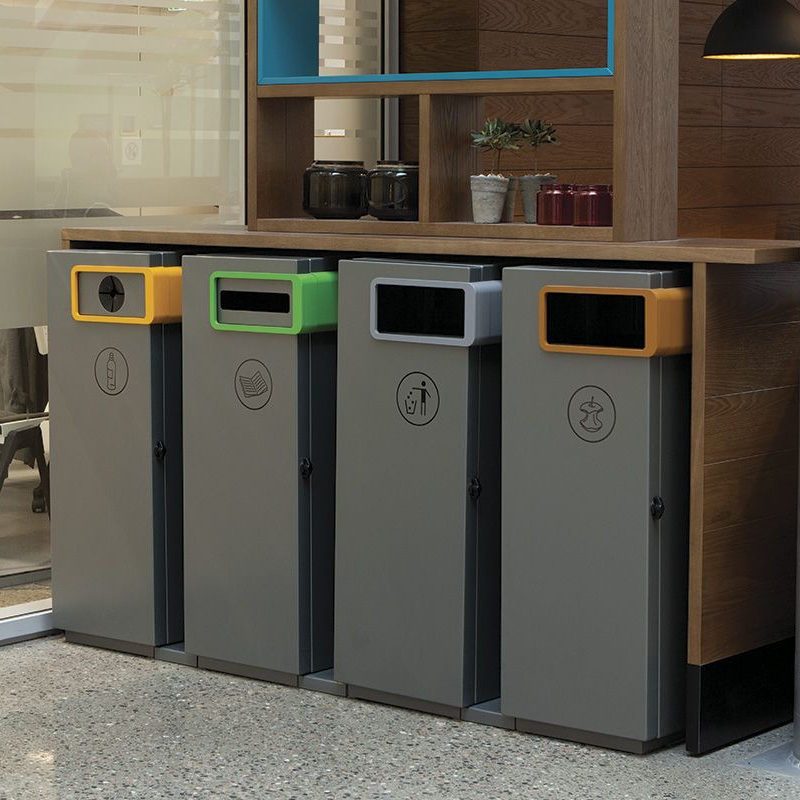 fire nobell avfallsbeholdere i en sorteringsstasjon inne, under en benkeplate. miljøbilde