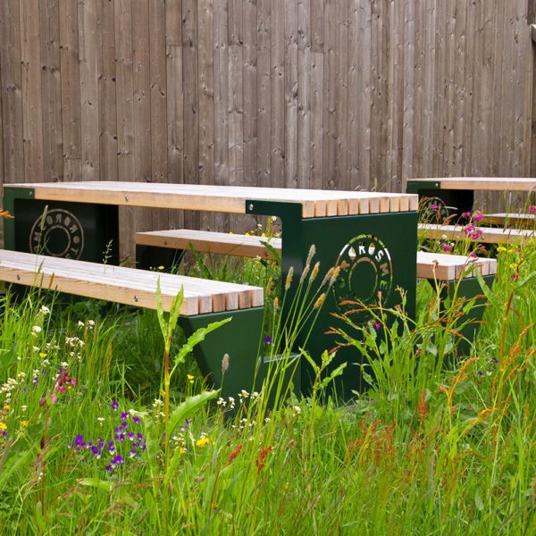 Rast "piknik-benk" lakkert i grønn og utskjært logo. Miljøbilde.